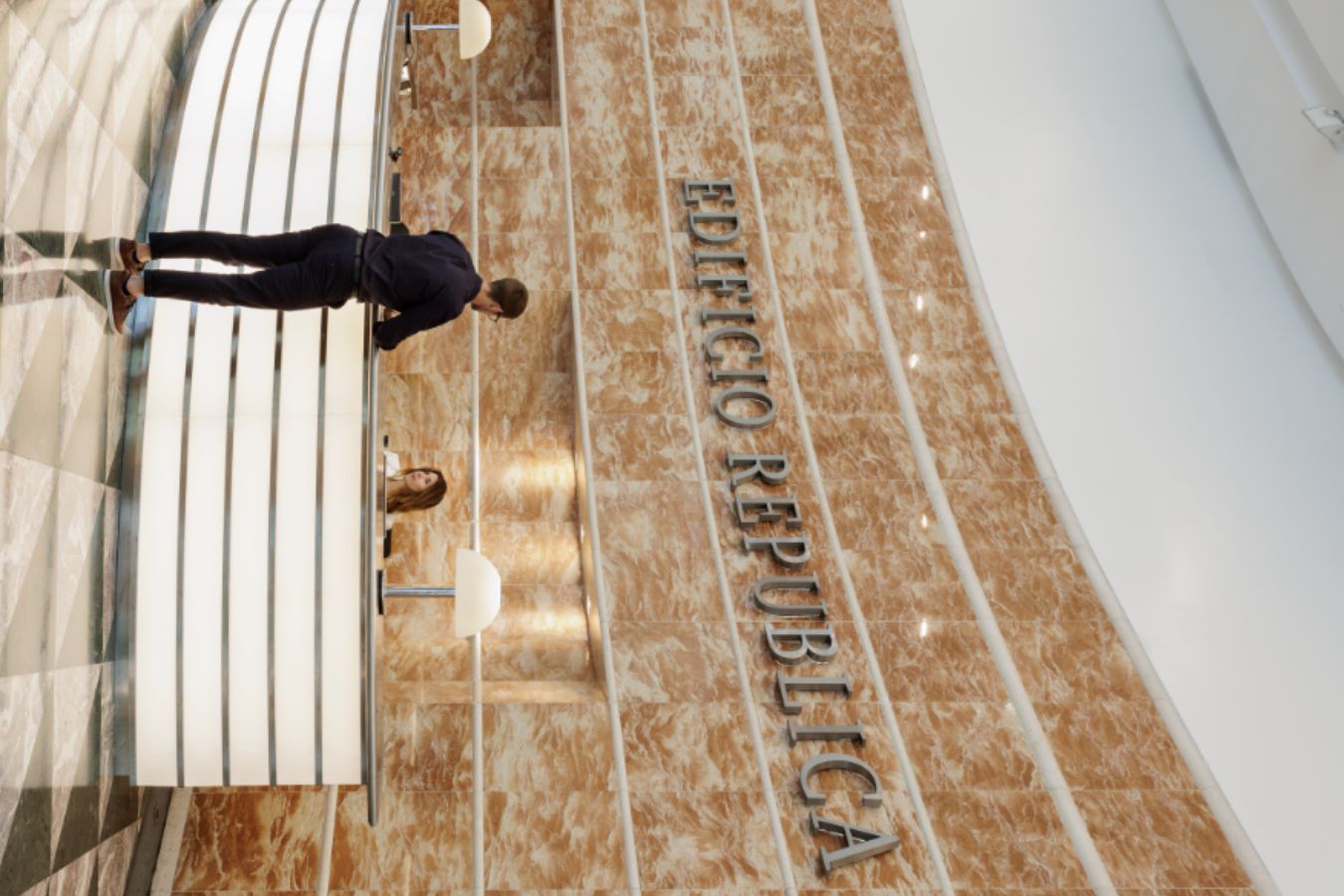 Edificio Republica - Elegant concierge desk with illuminated curve design and travertine wall cladding - Contract Workplaces.jpg